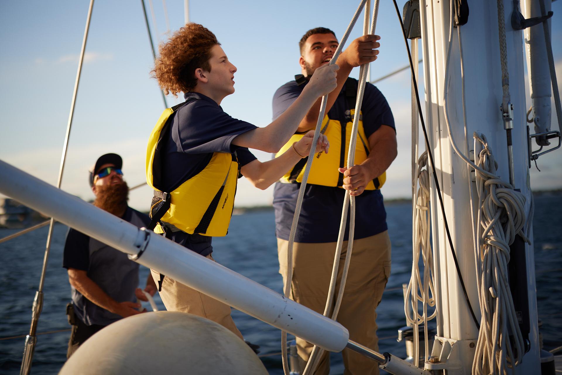 Crew hoisting the sails on the S/Y 'Whatever It Takes' sailing ketch.